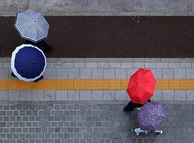 Pedestrians holding umbrellas walk along a street in downtown Seoul on Monday. (Yonhap News)