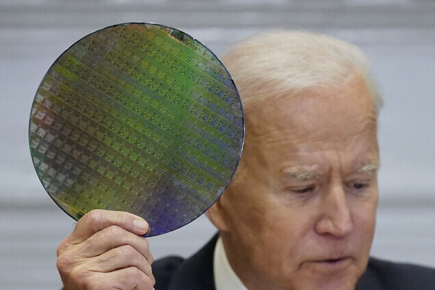 US President Joe Biden holds up a silicon wafer, as he participates virtually Monday in the CEO Summit on Semiconductor and Supply Chain Resilience in the White House. (AP/Yonhap News)