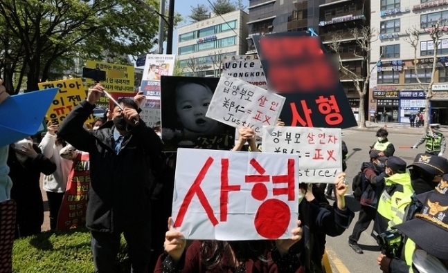지난 14일 오후 서울 양천구 서울남부지방법원 입구에서 시민들이 양모 장모(35)씨가 탑승한 것으로 보이는 호송차를 향해 팻말을 들고 항의하고 있다. 뉴시스