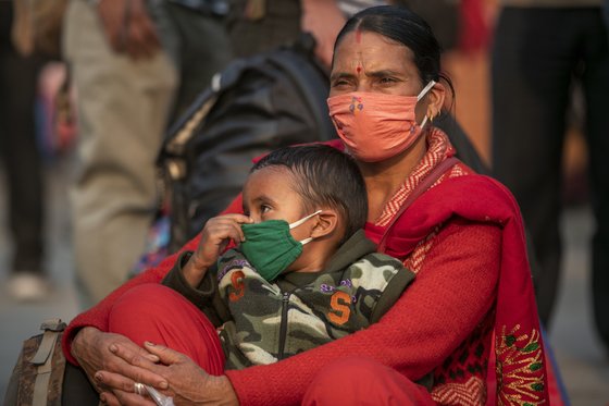 28일 네팔 카트만두에서 마스크를 낀 여성과 어린이가 버스를 기다리는 모습 [AP=연합뉴스]