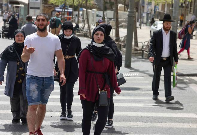 이스라엘이 실외 마스크 착용 의무를 해제한 첫날인 지난 18일 시민들이 마스크를 벗은 채 예루살렘 거리를 걸어가고 있다. [사진=연합뉴스]