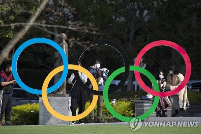 도쿄올림픽 박물관에서 시민들이 오륜 조형물을 배경으로 사진을 찍고 있다. [AP=연합뉴스 자료사진]