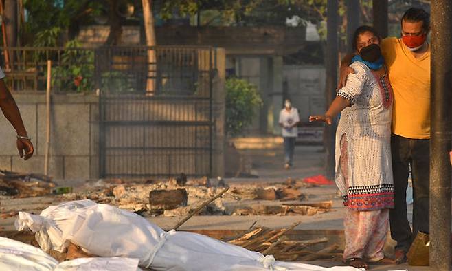 10일(현지시간) 인도 뉴델리에서 코로나19 유가족이 길거리에 놓인 시신 앞에서 슬퍼하고 있다. 뉴델리=EPA연합뉴스
