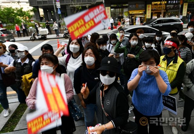 홈플러스 여성노동자들이 13일 서울 종로구 MBK파트너스 본사 앞에서 집단삭발 기자회견을 진행했다. 기자회견을 마친 뒤 참가자들이 MBK를 향해 경고문을 던지고 있다.