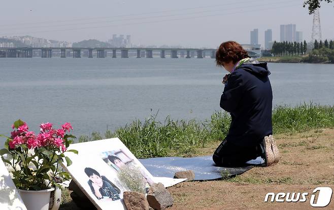 지난 19일 서울 반포한강공원 택시 승강장 인근에 마련된 손씨 추모 공간을 찾은 한 시민이 무릎을 꿇은 채 기도하고 있다/사진제공=뉴스1