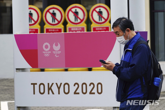[도쿄=AP/뉴시스]11일 일본 도쿄에서 코로나19 확산 방지를 위해 마스크를 쓴 한 남성이 2020 도쿄올림픽·장애인올림픽 홍보물 앞을 지나가고 있다. 2021.05.11.