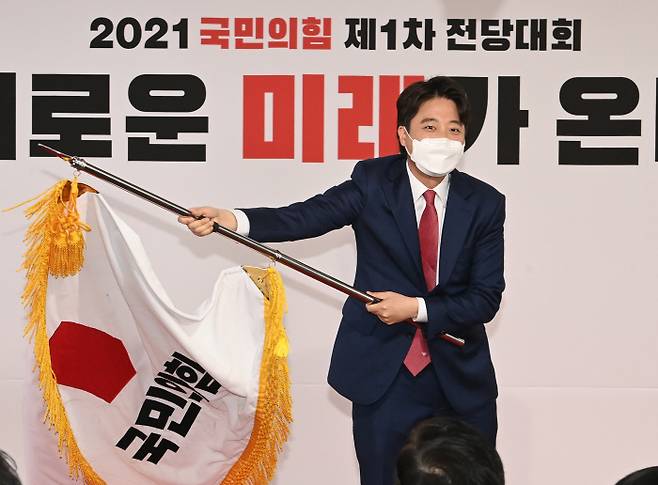 국민의힘 이준석 새 대표가 11일 서울 여의도 중앙당사에서 열린 전당대회에서 당기를 흔들고 있다. 연합뉴스