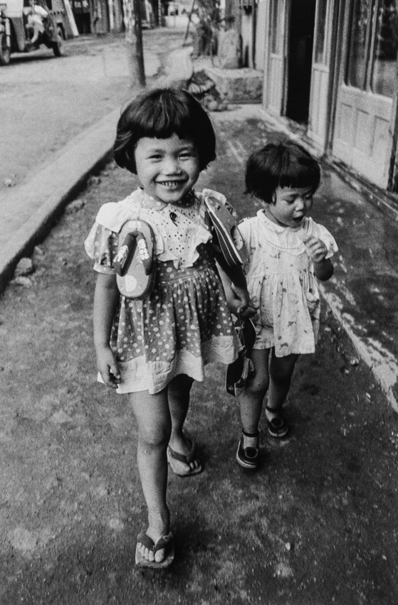 이노우에 코지의 사진작품. 새로 산 신발을 목에 걸고 동생과 함께 걸어가는 언니의 뿌듯한 웃음이 귀엽다. 일본, 후쿠오카, 1957년 7월. [사진 이노우에 코지 갤러리]