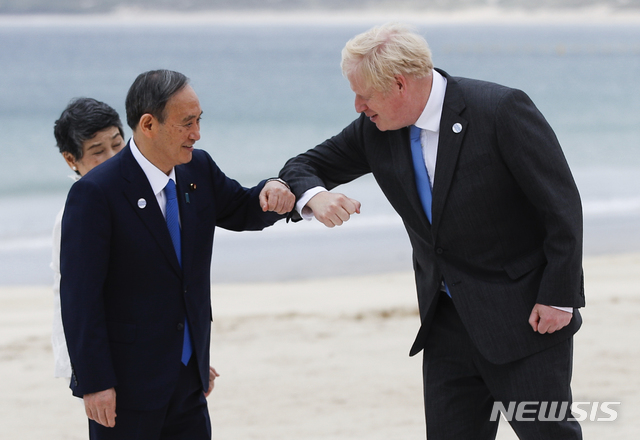 [콘월=AP/뉴시스]지난 11일(현지시간) 스가 요시히데 일본 총리(왼쪽)과 보리스 존슨 영국 총리가 콘월 카비스베이 해변에서 주요 7개국(G7) 정상회의 기념촬영에 임하기 전 팔꿈치 인사를 하고 있다.