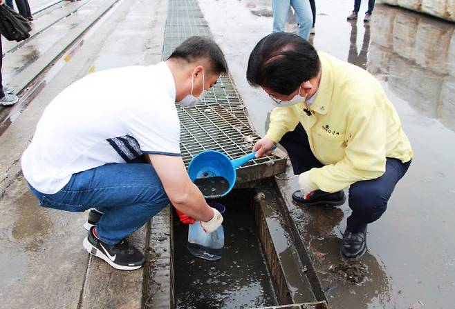강인규(오른쪽)나주시장이 지난달 15일 장성복물류터미널을 찾아 한난이 보관중인 SRF연료에 대해 현장점검을 진행하고 배수구에서 시료를 채취하고 있다. (사진=나주시청)