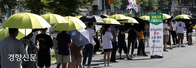 15일 서울 서초구 고속버스터미널 임시선별진료소에서 시민들이 햇볕을 피하기 위해 양산을 쓴 채 줄을 서서 순서를 기다리고 있다. 김창길 기자