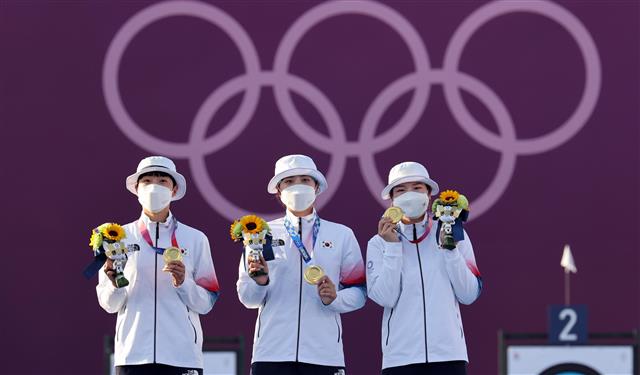 한국 여자 양궁 대표팀 안산(왼쪽부터), 장민희, 강채영 선수가 25일 일본 도쿄 유메노시마 공원 양궁장에서 열린 여자 양궁 단체전에서 금메달을 딴 뒤 시상식에 올라 금메달을 들어보이고 있다.도쿄 올림픽사진공동취재단