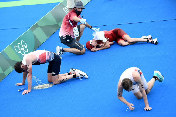 26일 오전 열린 도쿄올림픽 트라이애슬론 경기에서 레이스를 마친 선수들이 바닥에 쓰러져 구토하는 등 고통스러워하는 모습. AFP 연합