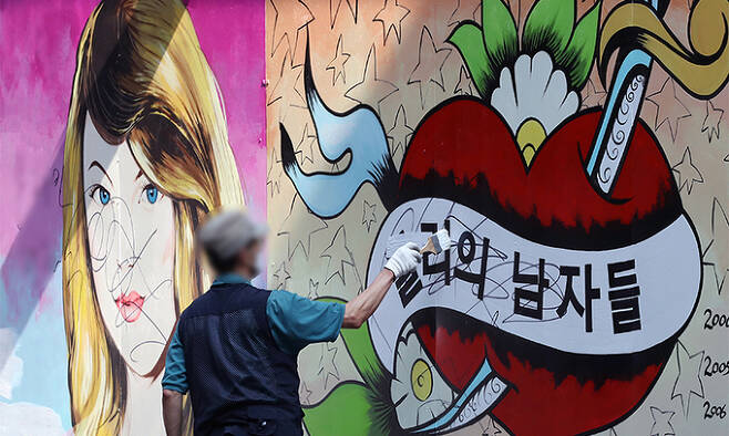 30일 서울 종로구의 한 서점 관계자가 외벽에 그려진 ‘쥴리 벽화’의 문구를 흰색 페인트로 덧칠하고 있다. 연합뉴스