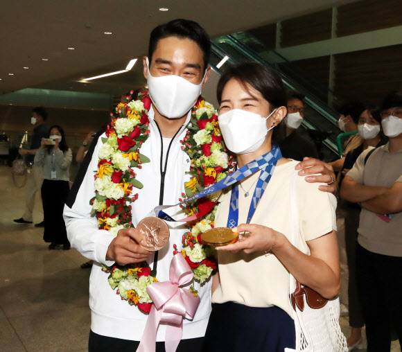 2020 도쿄올림픽 펜싱 남자 사브르 단체전을 우승하며 9년에 걸친 대회 2연패를 이끈 최고참 김정환이 29일 인천공항을 통해 입국, 4개월 만에 재회한 아내의 목에 메달을 걸어주고 있다.연합뉴스