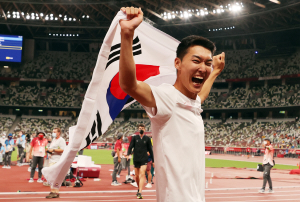 지난 1일 도쿄올림픽 남자 높이뛰기에서 2m35 한국신기록을 세우며 4위를 차지한 우상혁이 도쿄 올림픽스타디움에서 경기 종료 후 태극기를 펼치며 기뻐하고 있다. [사진 출처 = 연합뉴스]