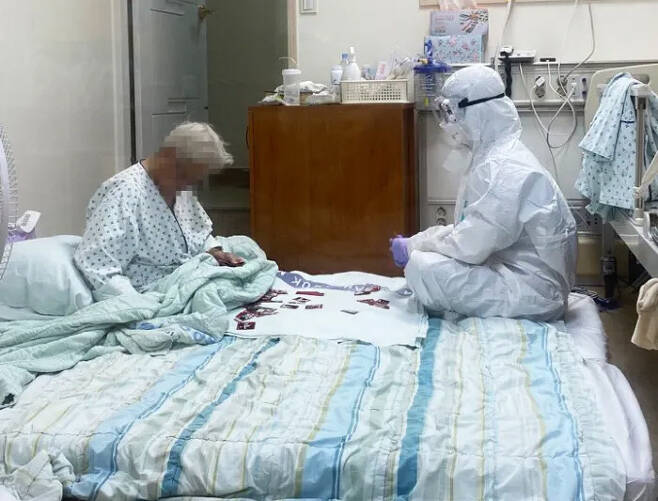 지난해 8월 삼육서울병원 코로나19 음압병상에서 박모 할머니와 간호사 이수련씨(오른쪽)가 화투를 이용해 그림 치료를 하는 모습. 대한간호협회 제공