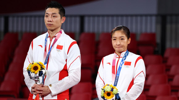 지난달 26일 도쿄올림픽 탁구 혼합복식 결승에서 일본에 져 은메달을 딴 중국 대표팀 쉬신(왼쪽)과 류스원이 침울한 표정으로 시상대에 서 있다. 이들은 금메달을 못 딴 데 대해 국민들에게 눈물로 사죄를 해야 했다.도쿄 로이터 연합뉴스