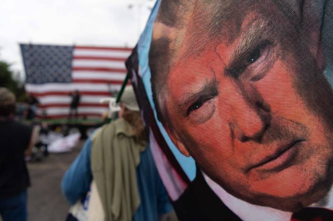 22일 미국 오리건주 포틀랜드에서 한 남성이 도널드 트럼프 전 대통령의 얼굴이 새겨진 깃발을 들고 시위에 나서고 있다. 트럼프 재임 시절 미국 민주당은 언론인보호법을 발의해 언론 탄압에 맞서고자 했다. /AFP연합뉴스