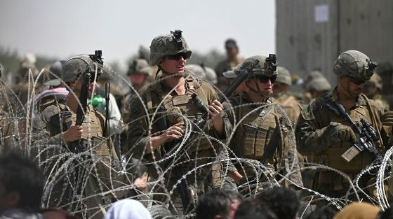 지난 20일 미군들이 아프간 카불 공항 인근 도로의 철조망 너머에서 아프간을 탈출하려는 사람들을 바라보고 있다. [AFP=뉴스1]