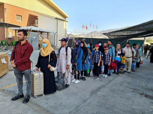 - 한국 정부와 협력한 아프가니스탄인들이 국내 이송을 위해 카불 공항에 도착한 한국 공군 수송기에 탑승하기 위해 줄을 서서 기다리고 있다. 2021.8.25 외교부 제공