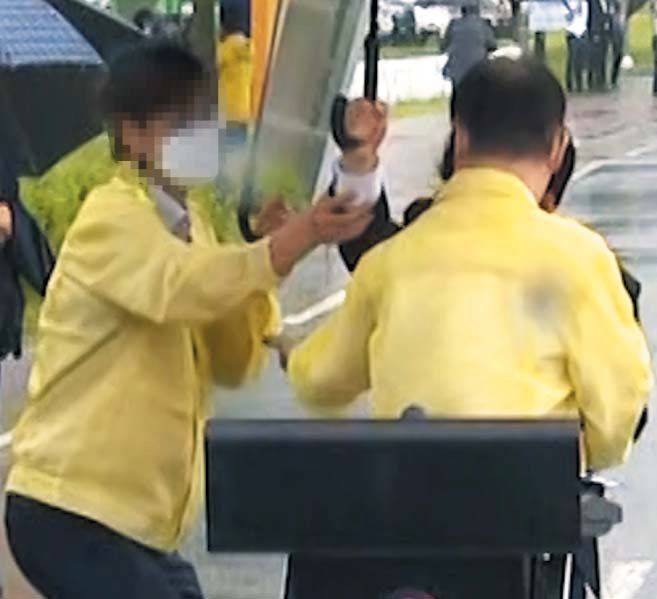 27일 오후 충북 진천 국가공무원인재개발원 정문 앞에서 민방위복을 입은 한 법무부 소속 검사(왼쪽)가 강성국(오른쪽) 법무부 차관에게 우산을 씌워주는 다른 직원의 손목 부분을 아래로 끌어 내리고 있다. 아프가니스탄 특별 입국자들의 정착 지원 방안 브리핑을 준비하는 강 차관 뒤쪽에서 기마 자세로 우산을 받치고 서 있던 직원은 강 차관이 브리핑하는 10분 중 3~4분가량을 땅바닥에 무릎을 꿇은 자세로 우산을 들고 있었다. /TV조선