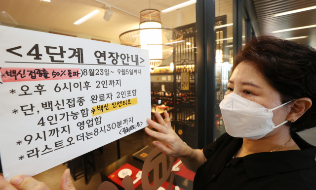 지난 22일 서울 양천구 한 중식당에서 관계자가 '백신 인센티브' 안내문을 붙이고 있다./연합뉴스