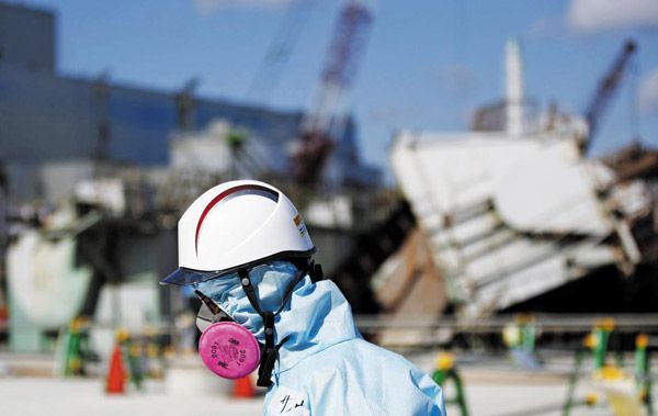 지난 2020년 7월 방호복에 방독면을 착용한 도쿄전력 직원이 일본 후쿠시마(福島) 제1원전 앞을 지나가고 있다. 직원 뒤로 원전 폭발 사고 당시 잔해들이 보인다. /조선DB