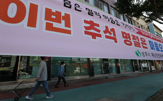 People in Sangju, North Gyeongsang Province, walk past a banner produced by the city’s Disease and Safety Countermeasure Headquarters advising limiting travel home over the Chuseok holiday one week away. (Yonhap News)
