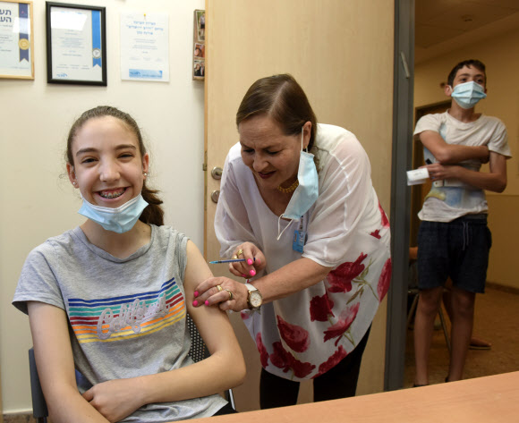 이스라엘, 다시 “실내마스크 써라”… 12~15세도 백신 접종  - 이스라엘 정부가 델타 변이를 중심으로 코로나19 재확산을 경고한 가운데 22일(현지시간) 예루살렘의 매카비 보건소에서 한 여학생이 화이자·바이오엔테크 백신을 맞고 있다. 백신 접종 효과에 힘입어 지난 15일부터 마스크 착용 의무를 완전 해제한 이스라엘에서 최근 12~15세 아동·청소년들의 집단감염 사례가 잇따르면서 당국은 이들에게 백신 접종을 강력히 권고하는 한편 집단감염이 발생한 일부 학교에 다시 마스크 착용을 의무화했다.예루살렘 UPI 연합뉴스
