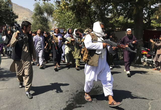 7일(현지시간) 아프가니스탄 수도 카불의 파키스탄대사관 인근에서 반(反)파키스탄 시위가 벌어진 가운데 총을 든 탈레반 대원들이 구호를 외치는 시위대를 향해 걸어가고 있다./AP연합뉴스
