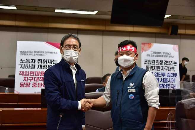 Seoul Metro CEO Kim Sang-bum (left) poses for a photo with Seoul Metro labor union head Kim Dae-hoon (right) after reaching an agreement over Seoul subway authority's restructuring plan. (Seoul Metro)