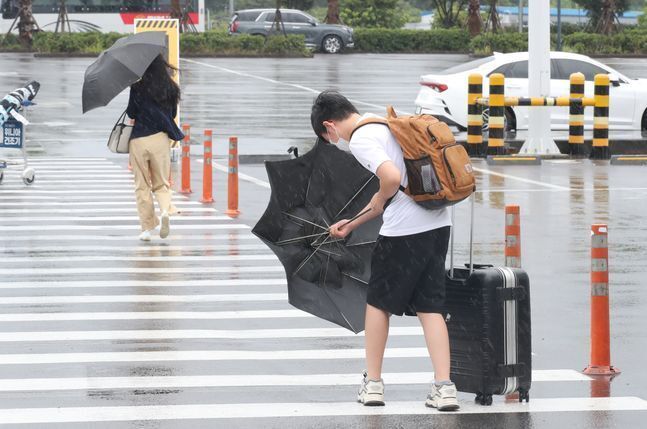 제14호 태풍 '찬투(CHANTHU)'가 북상 중인 지난 14일 오후 제주국제공항 내 렌터카 터미널에서 한 관광객이 힘겹게 우산을 펼치고 있다.ⓒ뉴시스