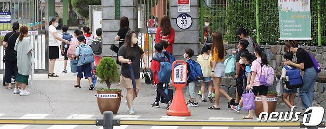 지난달 23일 서울의 한 초등학교에서 개학을 맞은 어린이들이 보호자와 함께 등교하고 있다. 2021.8.23/뉴스1 © News1 민경석 기자