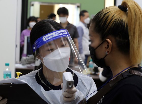 지난 14일 부산시민공원에 마련된 부산진구 코로나19 예방접종센터에서 외국인이 체온 검사를 받고 있다. [연합뉴스]