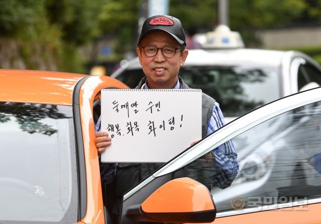 박세용 택시기사가 지난 6일 서울 용산구 효창공원 인근에서 둘째 딸에게 보내는 메시지를 들고 있다. 박씨는 "코로나 때문에 걱정이 돼서 울산에 살고 있는 둘째 딸에게 올라오지 말라고 했다"고 말했다.