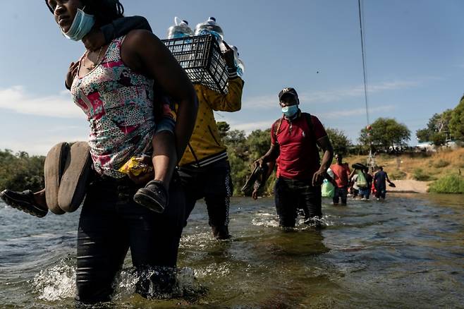 멕시코를 넘어 미국으로 입국하려는 이민자들이 물과 음식을 들고 리오그란데강을 건너고 있다./사진=로이터