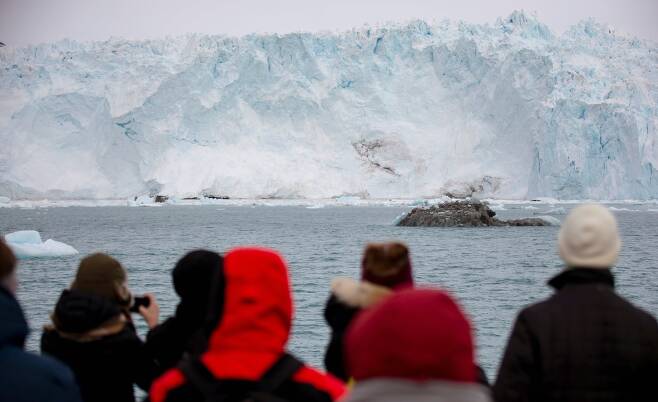 관광객들이 15일 일루리삿 앞바다에서 빙산이 부서지는 모습을 구경하고 있다. 로이터=연합뉴스