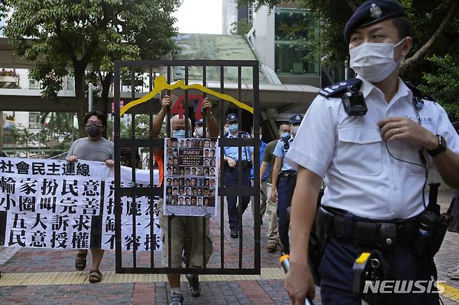 [AP/뉴시스] 19일 홍콩 선거위원 선발 투표에 반대하는 주민들이 경찰관이 지키는 투표소 앞에서 항의 시위하고 있다