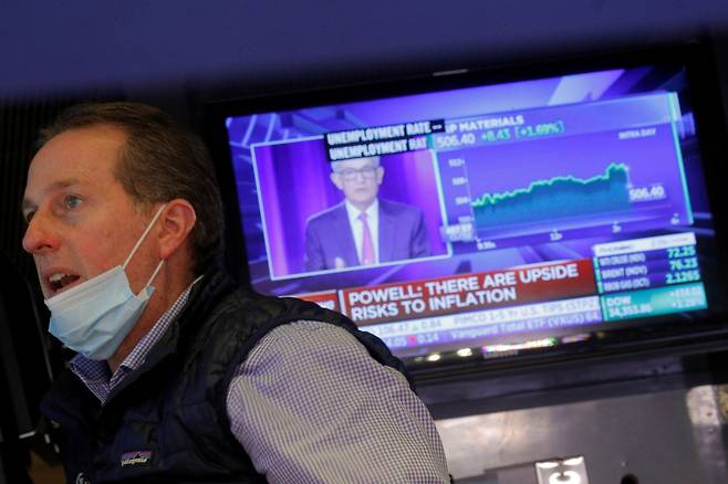 22일(현지시간) 미국 뉴욕증권거래소(NYSE)에서 제롬 파월 연방준비제도(Fed) 의장이 성명을 발표하는 모습이 TV 스크린에 비치는 가운데 한 트레이더가 업무를 처리하고 있다. /로이터 연합뉴스