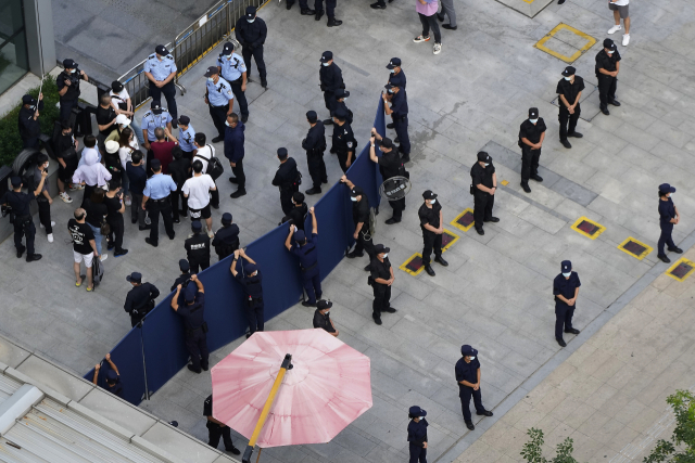 23일 파산 위기에 몰린 중국 대형 민간 부동산 개발업체 헝다 그룹의 광둥선 선전 본사 앞에서 건물 내 진입을 시도하는 투자자들이 공안과 경비원들에 둘러싸여 있다./AP연합뉴스