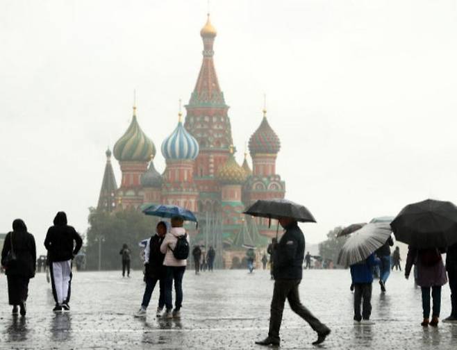 23일(현지시간) 러시아 수도 모스크바에 비가 내리는 가운데 시민들이 우산을 쓴 채 크레믈궁 앞을 지나고 있다. 모스크바=타스연합뉴스
