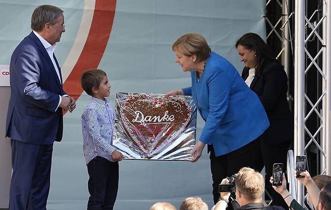독일 총선을 하루 앞둔 25일(현지시각) 기독민주연합과 기독사회연합의 총리 후보인 아르민 라셰트(왼쪽)의 지역구 아헨에서 지원 유세에 나선 앙겔라 메르켈(오른쪽) 총리가 한 어린이로부터 전통 쿠키를 선물 받고 있다. 메르켈 총리는 이번 총선을 끝으로 16년간의 집권을 마치고 정계를 은퇴한다. 아헨/연합뉴스