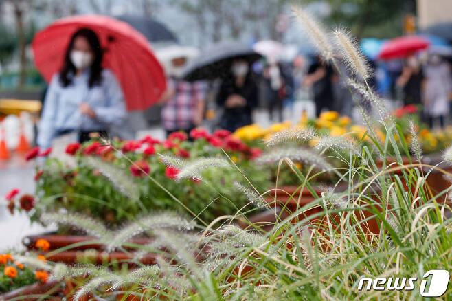 서울 중구 청계광장에 있는 수크령 너머로 우산 쓴 시민들이 출근하고 있다. © News1 안은나 기자