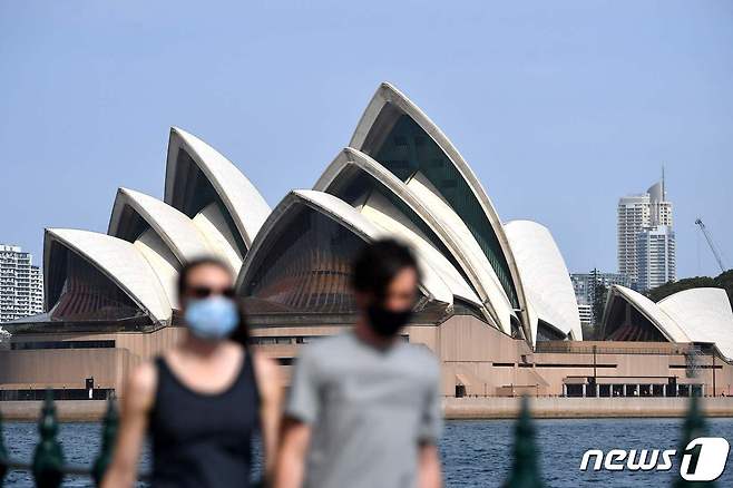 10일(현지시간) 호주 시드니에서 마스크를 쓴 시민들이 오페라하우스 인근 도보를 걷고 있다. 2021.09.10 © AFP=뉴스1