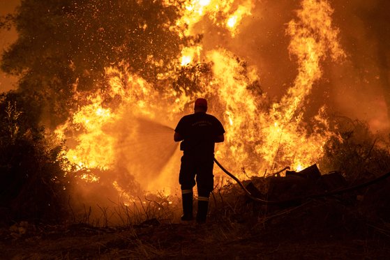 지난달 초 그리스 에비아 섬에서 소방관이 산불을 진압하기 위해 물을 뿌리고 있다. [사진 로이터]