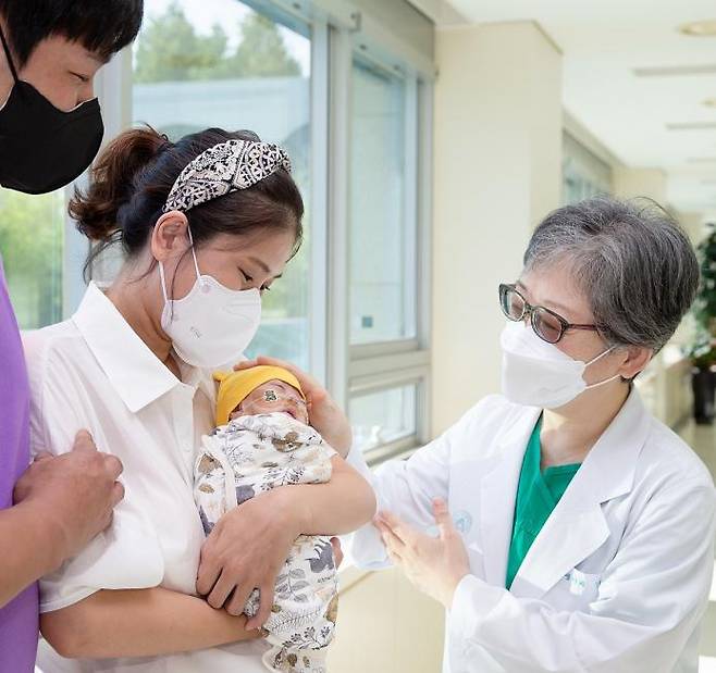 김애란 서울아산병원 신생아과 교수가 엄마 품에 안겨 있는 건우의 머리를 쓰다듬으며 퇴원 축하 인사를 건네고 있다. 서울아산병원 제공