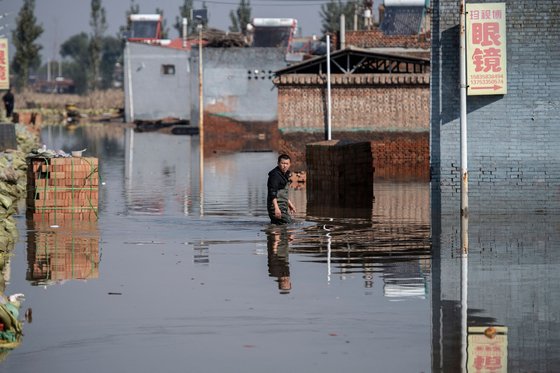 중국 북부 산시성에 이상 기후로 폭우가 쏟아져 마을이 물에 잠기자 한 남성이 망연자실한 표정을 짓고 있다.[AFP=연합뉴스]