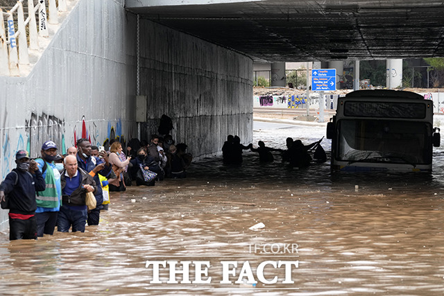14일(현지시간) 그리스 수도 아테네에 폭풍우가 강타한 가운데 침수된 지하도에 갇힌 버스에서 승객들이 높은 수위의 물 속을 걸으며 대피하고 있다. / 아테네=AP.뉴시스