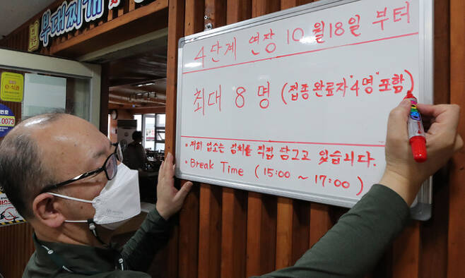 서울 종로구의 한 음식점 관계자가 15일 식당 출입 인원을 최대 8명으로 수정하고 있다. 정부는 단계적 일상회복 전환 준비단계로 오는 18일부터 수도권에서 백신 미접종자 4명을 포함해 최대 8명까지 모임을 할 수 있도록 하는 사회적 거리두기 조정안을 이날 발표했다. 뉴시스